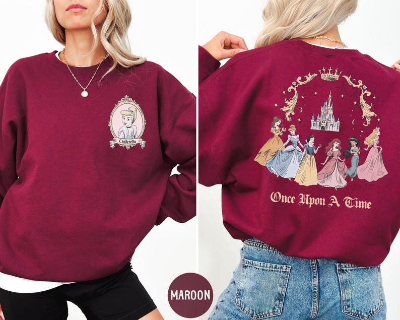 A woman wearing a burgundy sweatshirt with a Disney princess design on the front and back.