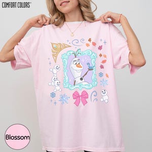A woman wearing a pink t-shirt with a design featuring characters from the Disney movie Frozen.
