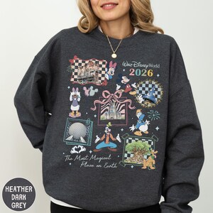 A woman wearing a gray sweatshirt with a collage of Disney-themed illustrations and text.