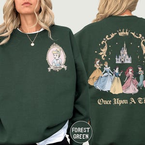 A woman wearing a green sweatshirt with a Disney princess design on the front and back.