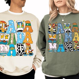 two people wearing sweatshirts with colorful, cartoon-style text and characters on them.