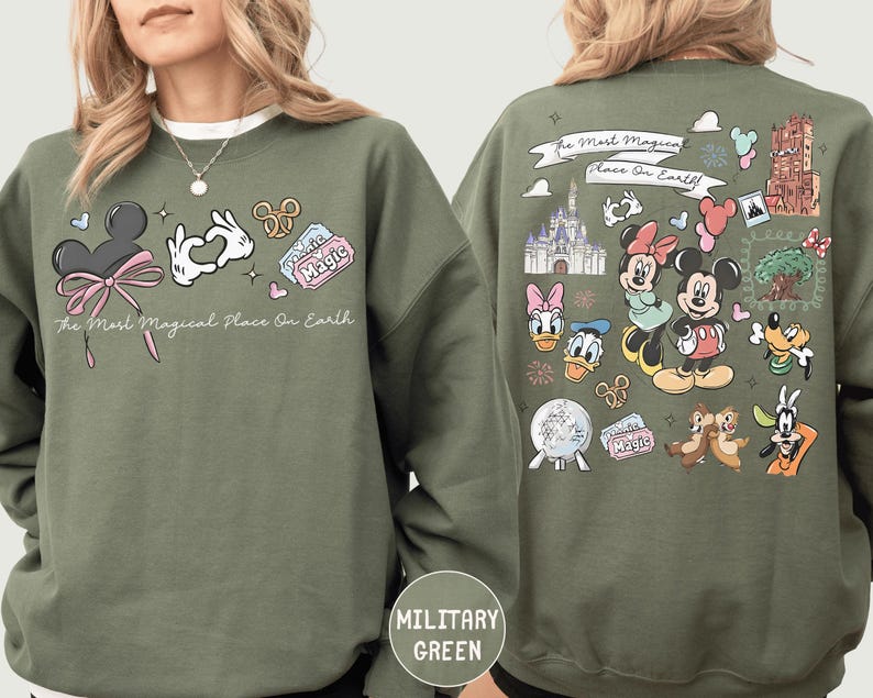 A woman wearing a green sweatshirt with various Disney characters and Disney-themed graphics printed on it.