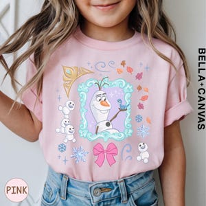 A young girl wearing a pink t-shirt with a graphic design featuring characters from the Disney movie Frozen.