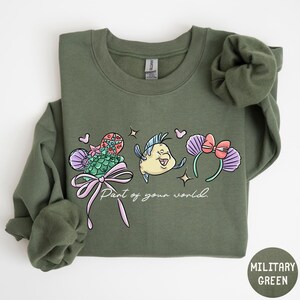 A green sweatshirt with a cartoon fish and various colorful elements printed on it.