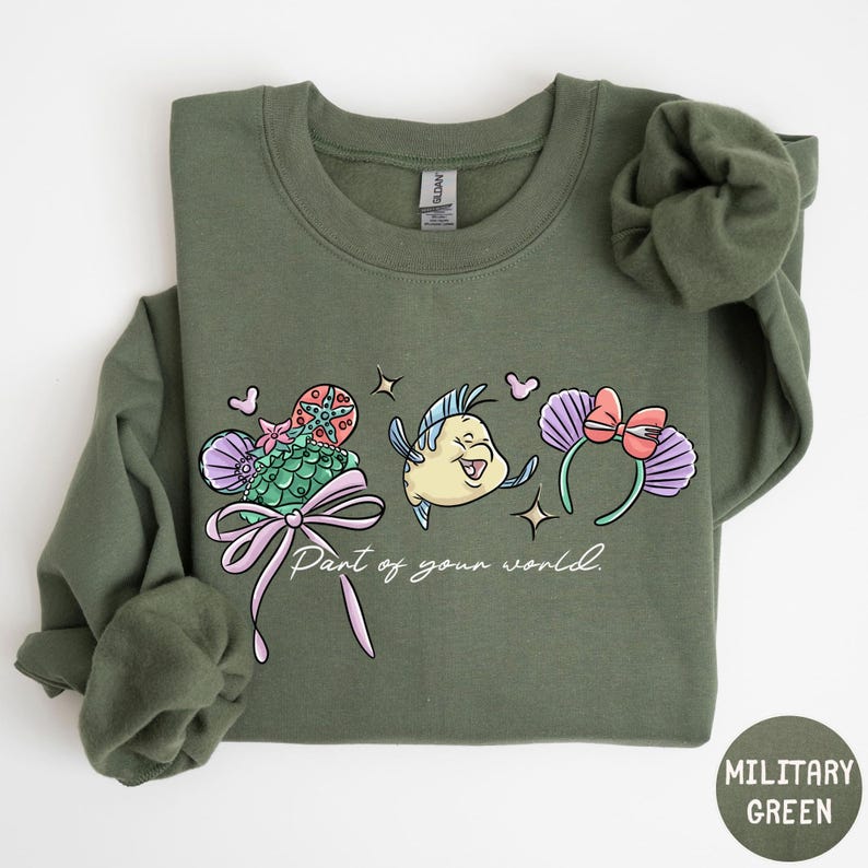 A green sweatshirt with a cartoon fish and various colorful elements printed on it.