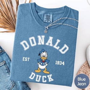 A blue t-shirt with a cartoon image of Donald Duck and text that says "DONALD EST. 1934 DUCK" printed on it.