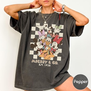 A person wearing a black t-shirt with a graphic of Disney characters and text.