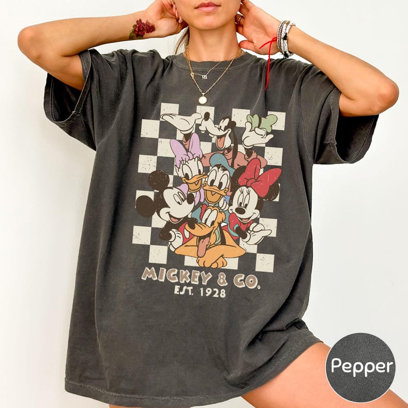 A person wearing a black t-shirt with a graphic of Disney characters and text.