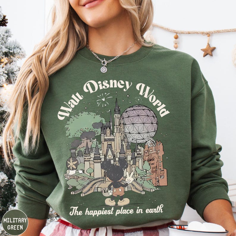 A woman wearing a green sweatshirt with a graphic of Disney World and the text "The happiest place in earth" printed on it.
