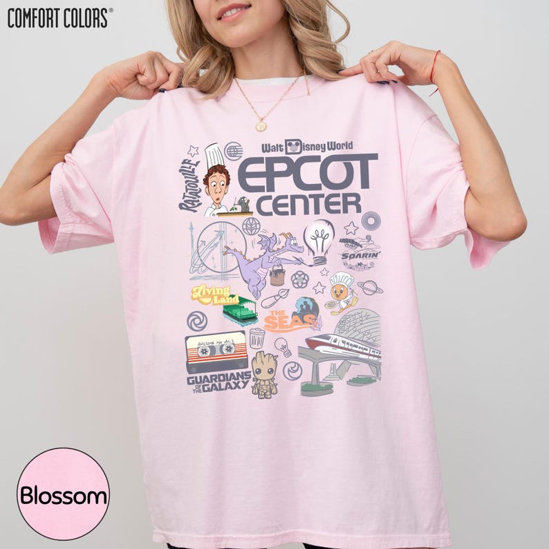 A woman wearing a pink t-shirt with various Disney-themed graphics and text, including characters, logos, and other iconic elements associated with the Walt Disney World Epcot Center.