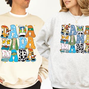 two people wearing sweatshirts with colorful, cartoon-style text and characters on them.