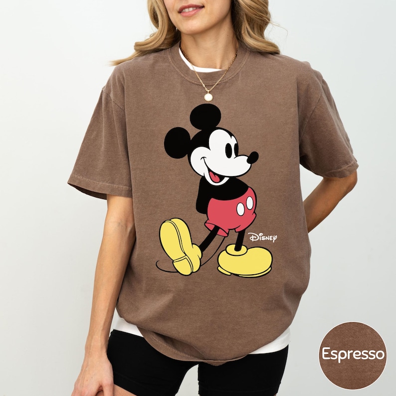 A woman wearing a brown t-shirt with a Mickey Mouse graphic printed on it.