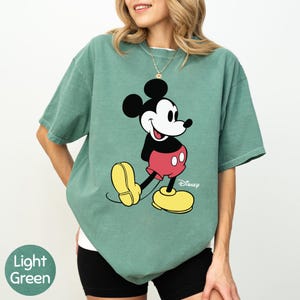 A woman wearing a green t-shirt with a cartoon character printed on it.