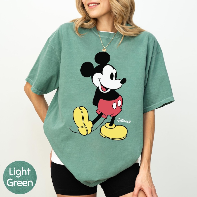 A woman wearing a green t-shirt with a cartoon character printed on it.