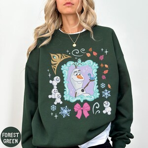 A woman wearing a green sweater with a graphic of a character from the Disney movie Frozen.