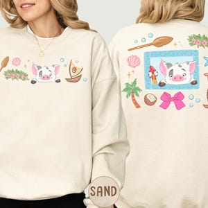 a woman wearing a white sweatshirt with a colorful and whimsical design on the back.
