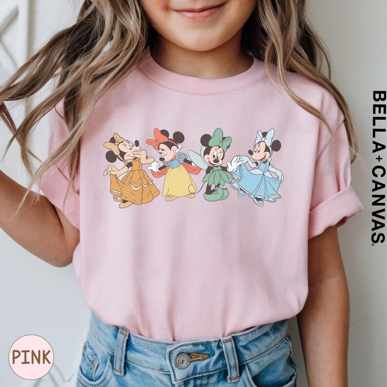 A young girl wearing a pink t-shirt with a graphic of four Disney Minnie Mouse characters.