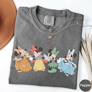 A gray t-shirt with a graphic of four cartoon Minnie Mouse characters in different outfits, including a yellow dress, a blue dress, a green dress, and a pink dress.