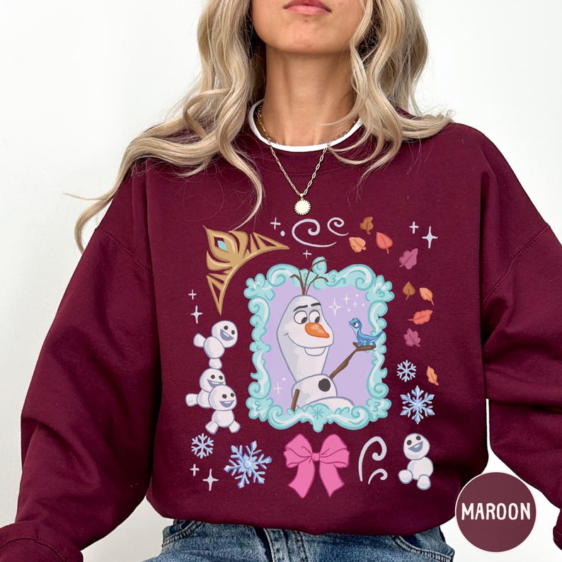 A woman wearing a burgundy sweatshirt with a graphic design featuring characters from the Disney movie Frozen.