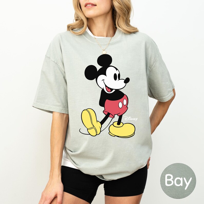A woman wearing a gray t-shirt with a Mickey Mouse graphic printed on it.