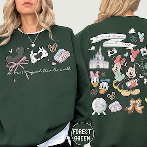 A woman wearing a green sweatshirt with various Disney characters and Disney-themed graphics printed on it.