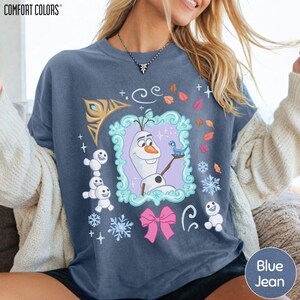 A woman wearing a blue t-shirt with a graphic design featuring characters from the Disney movie Frozen.