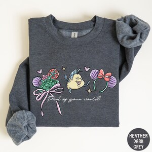 A gray sweatshirt with a graphic design featuring a cartoon character and the text "Paint of your world" printed on it.
