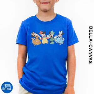 A young boy wearing a blue t-shirt with a line of four Disney Minnie Mouse characters.