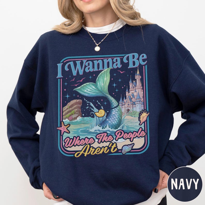 A navy blue sweatshirt with a colorful graphic design depicting a mermaid, castle, and text.