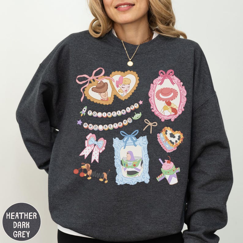 A woman wearing a gray sweatshirt with various cartoon-style illustrations and text on it.