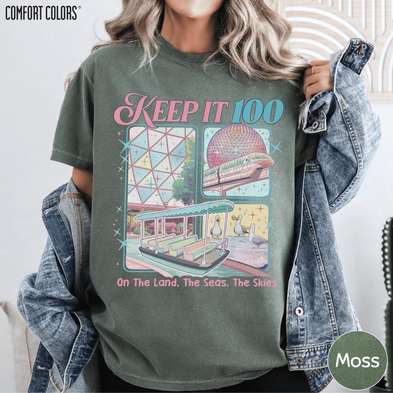 A woman wearing a green t-shirt with a graphic design featuring a space-themed illustration and text.