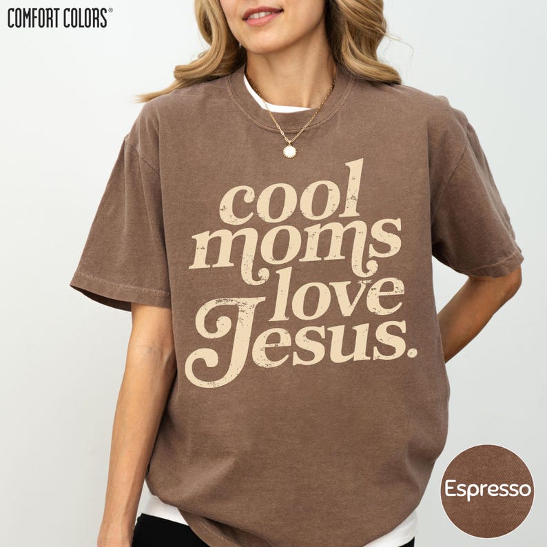 A woman wearing a brown t-shirt with the text "cool moms love Jesus" printed on it.