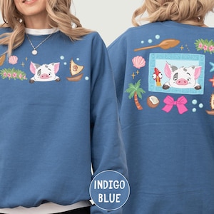 A woman wearing a blue sweatshirt with a pig design and various other colorful elements on the back.