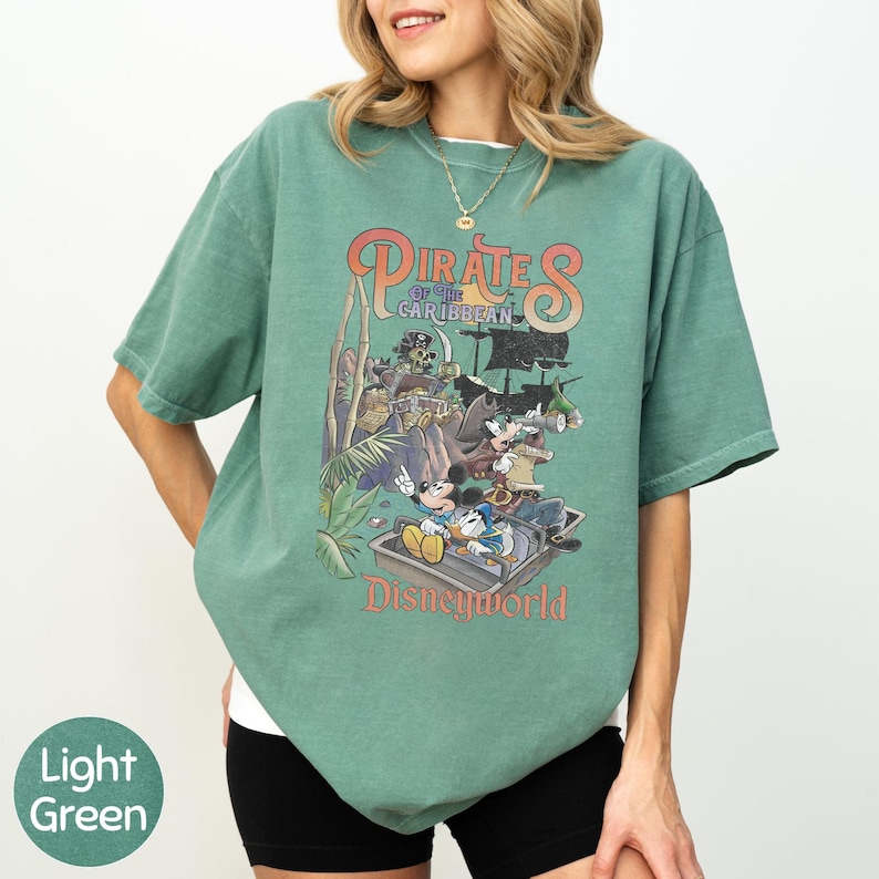 A woman wearing a green t-shirt with a graphic of Disney characters from the Pirates of the Caribbean ride at Disneyworld.