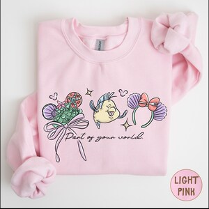A pink sweatshirt with a cartoon character and text printed on it.