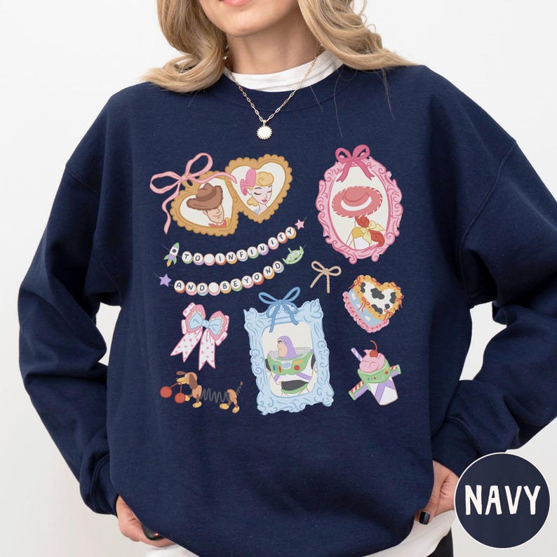 A navy blue sweatshirt with various cartoon-style illustrations and text, including a heart, bow, and other whimsical designs.