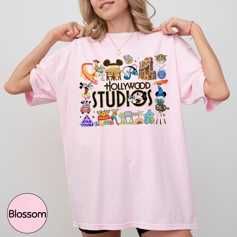 A woman wearing a pink t-shirt with various Disney and Hollywood Studios logos and characters on it.