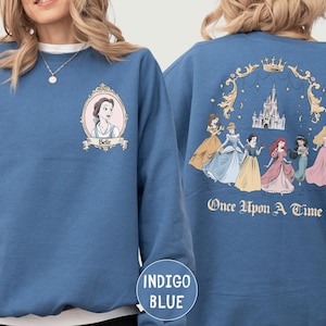 A woman wearing a blue sweatshirt with a Disney princess design on the front and a castle illustration on the back.