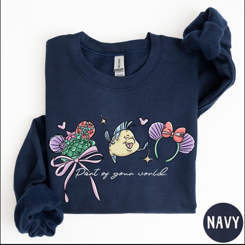 A navy blue sweatshirt with a colorful graphic design featuring a cartoon fish and flowers, along with the text "Part of your world."