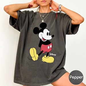A woman wearing a gray t-shirt with a Mickey Mouse graphic printed on it.