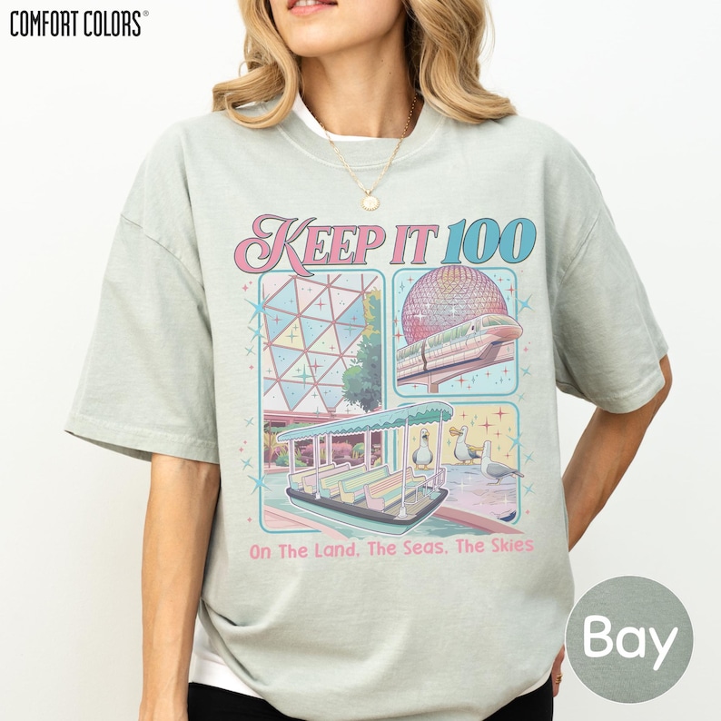 A woman wearing a t-shirt with a graphic design featuring a beach scene and a cruise ship.