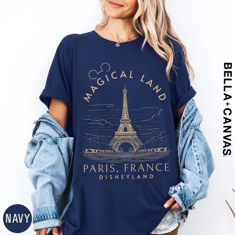 A woman wearing a navy blue t-shirt with a graphic design of the Eiffel Tower and text that says "Magical Land Paris, France Disneyland".