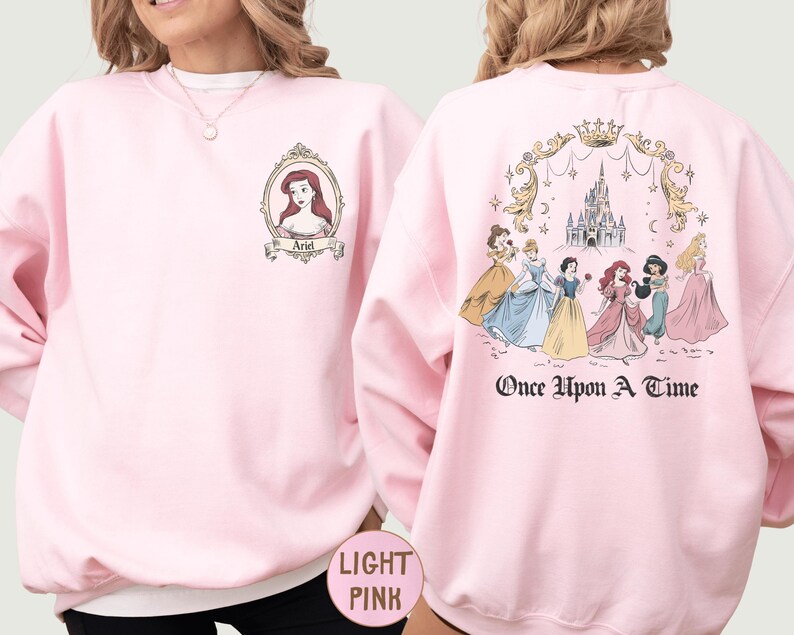 A woman wearing a pink sweatshirt with a design featuring Disney princesses and the text "Once Upon a Time" on the back.