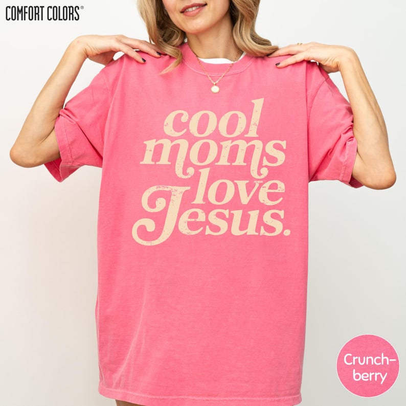 A woman wearing a pink t-shirt with the text "cool moms love Jesus" printed on it.