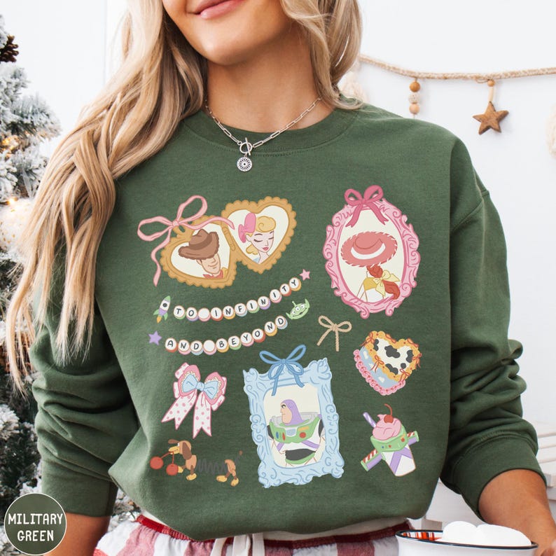 A woman wearing a green sweatshirt with various cartoon-style illustrations and text on it.