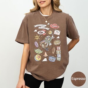 A woman wearing a brown t-shirt with various cartoon characters and icons printed on it.