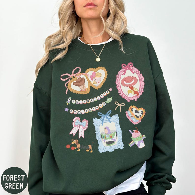 A woman wearing a green sweatshirt with various colorful and whimsical illustrations, including hearts, bows, and other decorative elements.