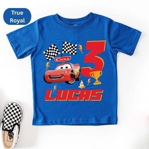 A blue t-shirt with a design featuring a red car and the number 3, along with the text "Cars 3 LUCAS".