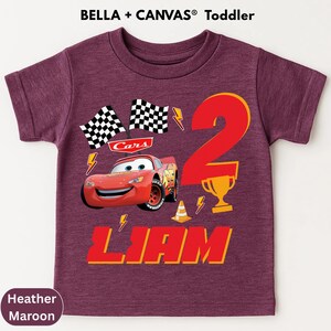 A purple t-shirt with a design featuring the character Lightning McQueen from the Cars movie, along with a number 2 and the text "Liam".