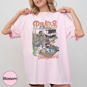 A woman wearing a pink t-shirt with a graphic of Disney characters from the Pirates of the Caribbean ride at Disneyworld.